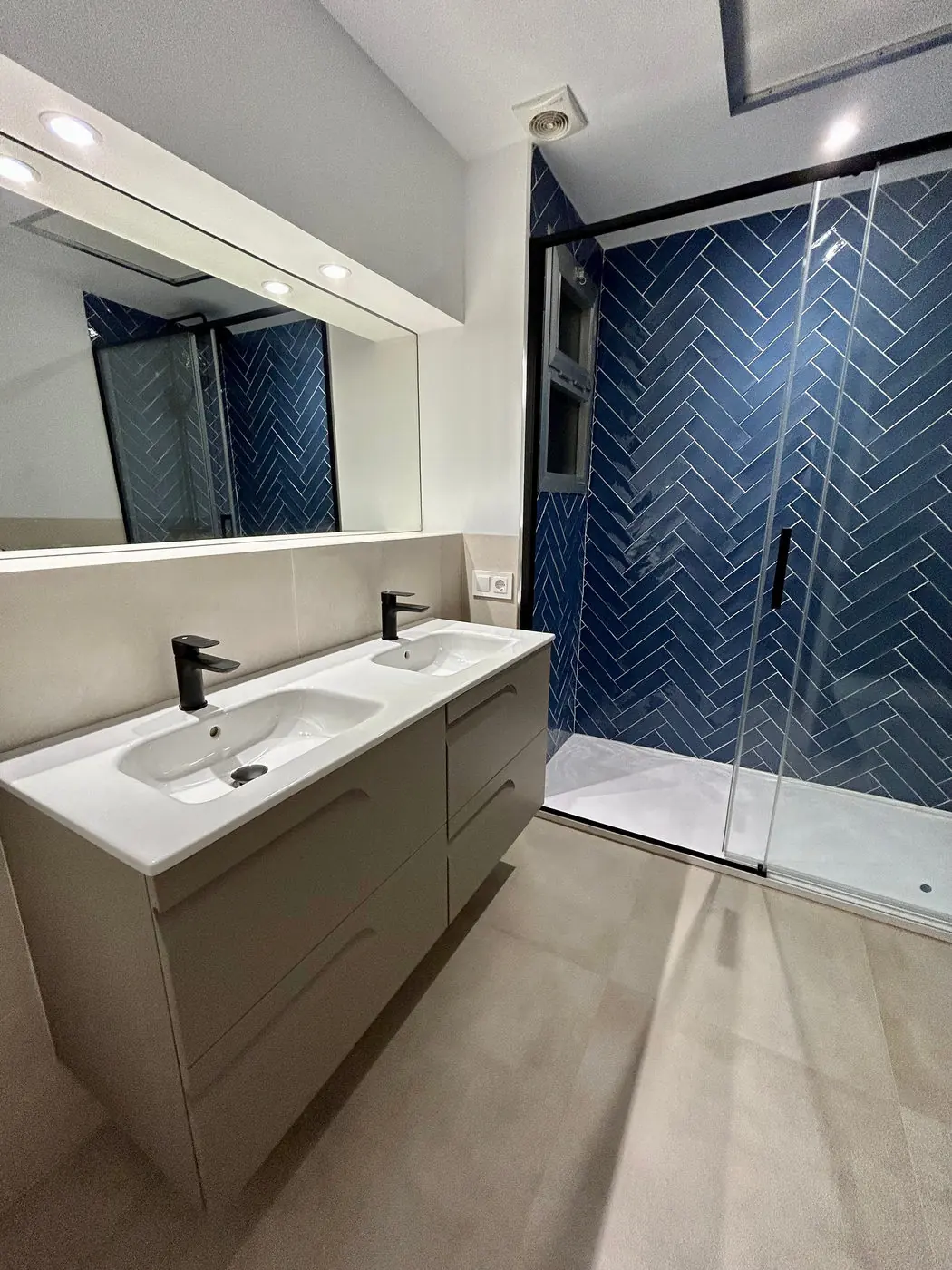 Baño reformado con azulejo azul y mueble de lavabo suspendido