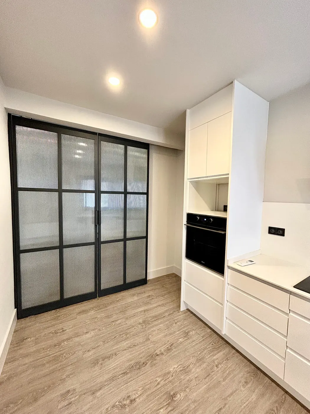 Cocina separada del salón con cerramiento de cristal y perfil negro