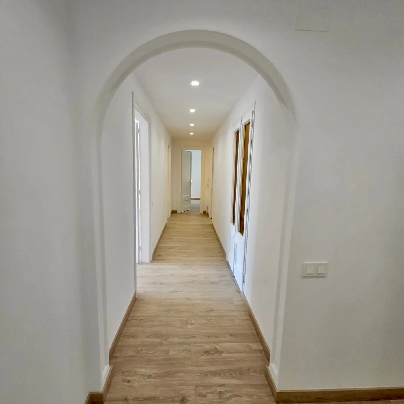 Pasillo reformado con suelo nuevo e iluminación empotrada