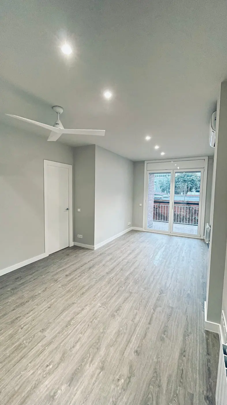 Salón de una vivienda tras una reforma integral, con suelo de madera y paredes blancas